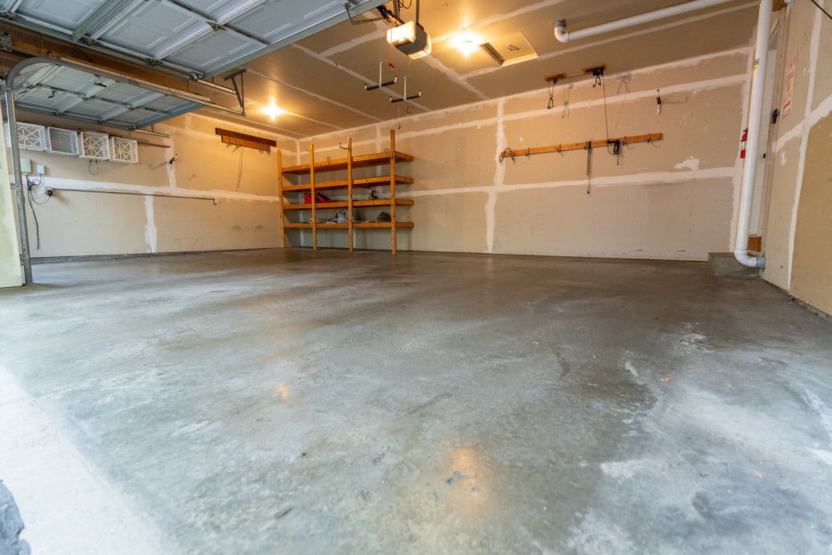 Spacious garage with polished concrete floor and wooden shelving on the wall.